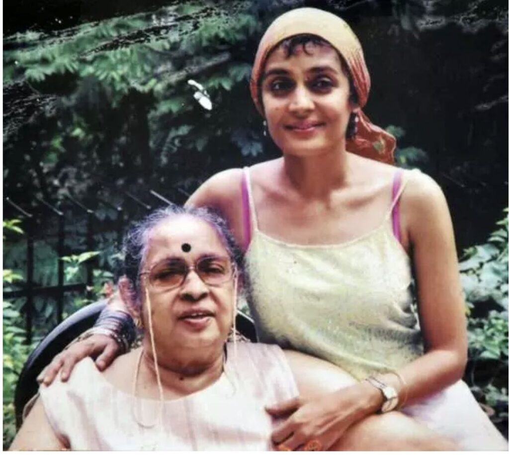 A photo from the 1990s. The photo shows a young girl, Arundhati, sitting next to her mother, with her hand on her shoulder. Her mother is sitting in a chair, and Arundhati is sitting right next to her.
ভালোবাসা