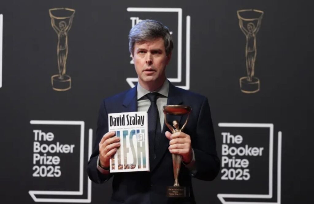 Author David Szalay holding his novel Flesh and the Iris trophy at The Booker Prize 2025 ceremony.