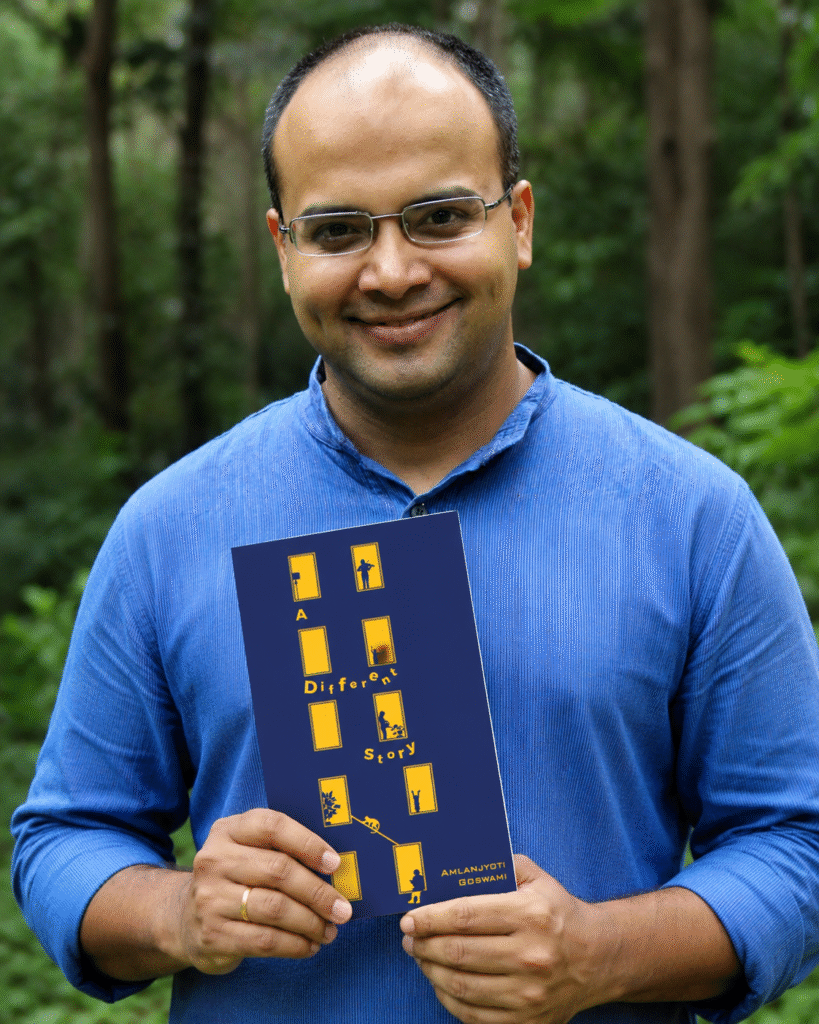 Author Amlanjyoti Goswami holding his book A Different Story in a natural outdoor setting. A professional promotional author photo showcasing the book cover, perfect for book reviews, author interviews, publisher websites, Amazon author pages, Goodreads profiles, and literary marketing
